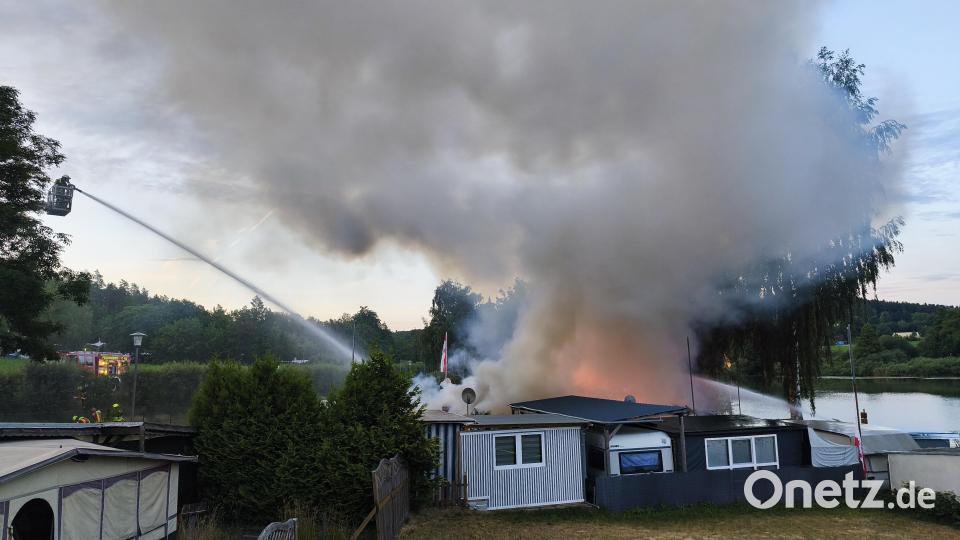 Per Drehleiter von der Straße aus bekämpfen die Feuerwehrleute den Brand auf dem Campingplatz am Rußweiher. Bild: Jürgen Masching