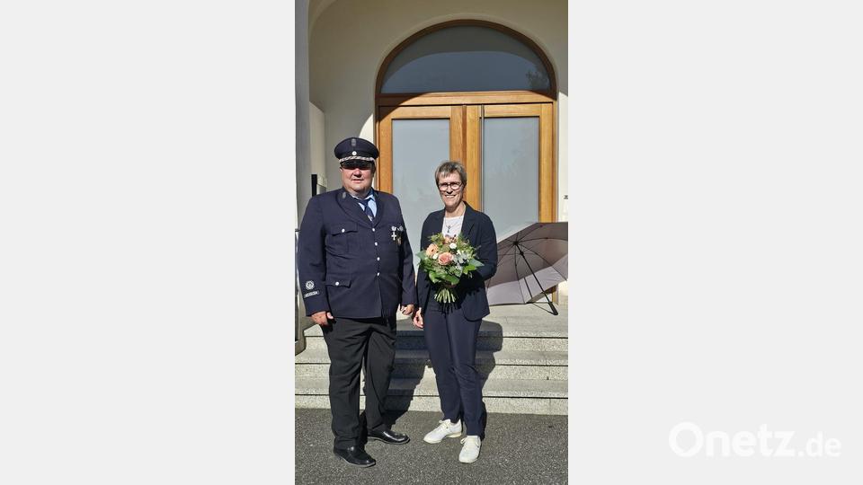 Mit einem Blumenstrauß begrüßte Feuerwehrvorstand Matthias Reul Schirmherrin Marion Höcht. Nach der Begrüßung folgte die Gedenkfeier am Friedenshain mit der Niederlegung eines Blumengestecks. Bild: Verena Schieder