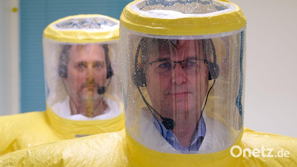 Über Funk bekommen die Ärzte wie Björn Jensen (rechts) Anweisungen, wie genau sie die Anzüge mit Säure abduschen müssen. (Archivbild) Bild: Bernd Thissen/dpa