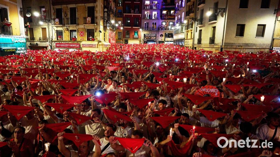 Die Feiernden halten Kerzen und rote Halstücher in den Händen. Bild: Miguel Oses/AP/dpa