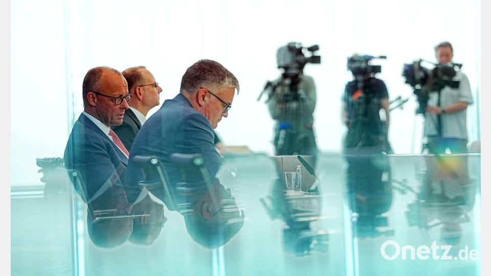 Bundeskanzler Friedrich Merz (l, CDU) sitzt bei der traditionellen Sommer-Pressekonferenz im Haus der Bundespressekonferenz (BPK) neben Regierungssprecher Stefan Kornelius (vorne, 3.v.l). Bild: Michael Kappeler/dpa