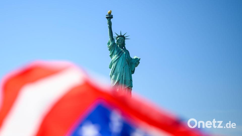 Die Fahne der USA weht vor der Freiheitsstatue. Bild: Tom Weller/dpa