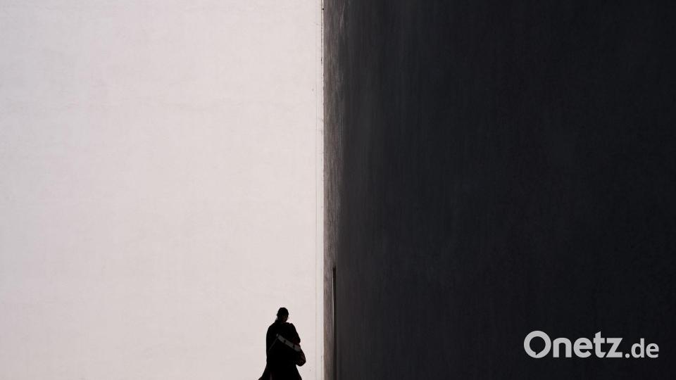 Eine Frau zeichnet sich als Silhouette vor der sonnenbeschienenen Fassade eines Gebäudes in in Kalifornien ab. Bild: Jae C. Hong/AP/dpa