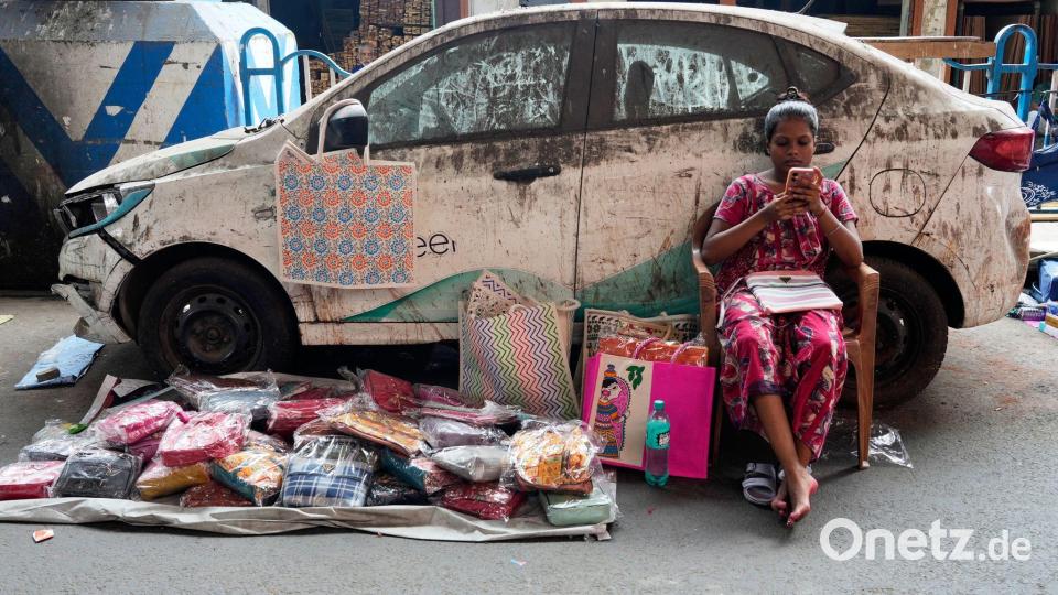 Indien - Verkäuferin mit Handy verkauft Taschen Bild: Bikas Das/AP/dpa