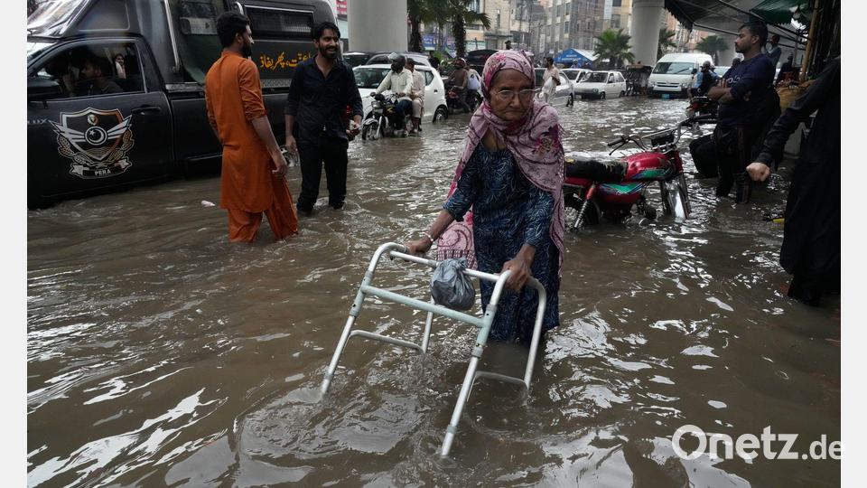 Eine ältere Frau watet durch eine von starken Monsunregenfällen überflutete Straße. Bild: K.M. Chaudary/AP/dpa