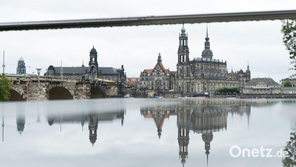 Die Kulisse der Altstadt spiegelt sich in einem mit Regenwasser benetzten Tisch einer geschlossenen Freiluftgaststätte. Bild: Sebastian Kahnert/dpa