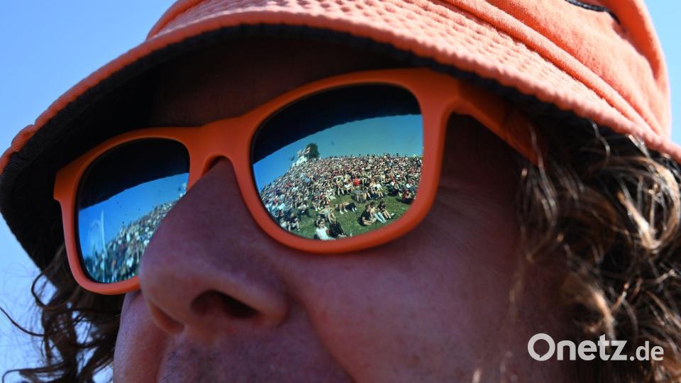 In der Sonnenbrille eines Besuchers spiegelt sich bei dem Musikfestival „Das Fest“ der gut gefüllte Hügel auf der Günther-Klotz-Anlage in Karlsruhe. Bild: Jennifer Kramer/dpa