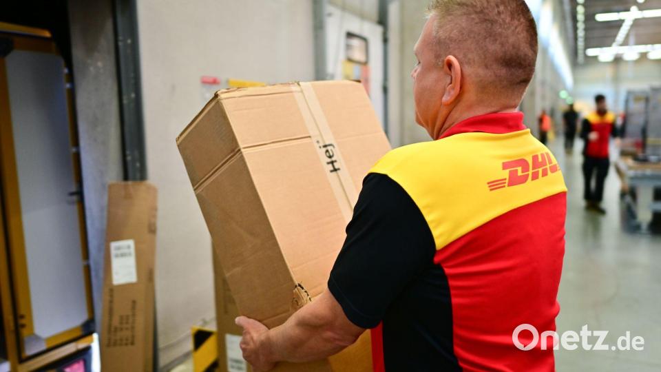 Ein Paketbote schleppt in einem DHL-Standort ein schweres Paket. (Archivbild) Bild: Sebastian Christoph Gollnow/dpa