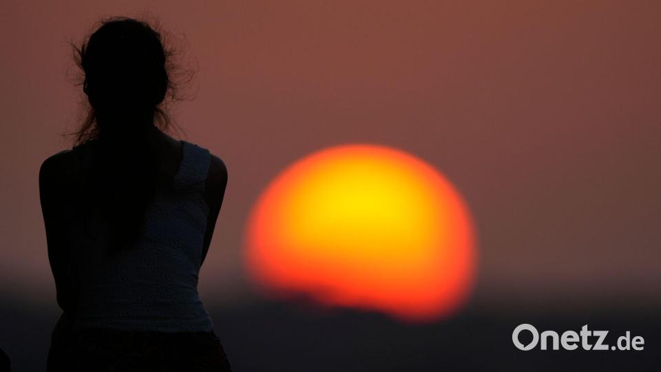 Eine Frau beobachtet den Sonnenuntergang. Bild: Charlie Riedel/AP/dpa