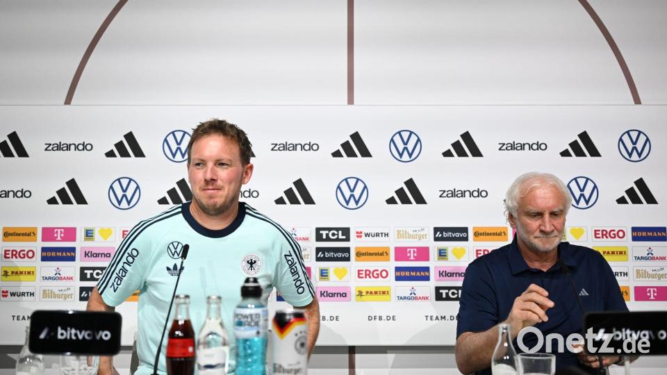 Bundestrainer Julian Nagelsmann (l) und Rudi Völler, DFB-Sportdirektor, sitzen auf dem Podium. Bild: Federico Gambarini/dpa
