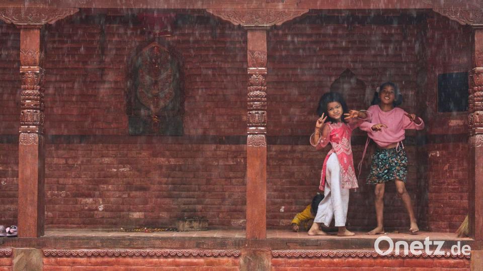 Kinder gestikulieren, während sie bemerken, dass sie während des Monsuns fotografiert werden. Bild: Niranjan Shrestha/AP/dpa