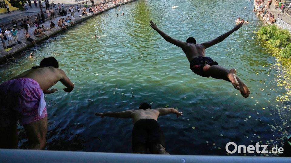Während einer Hitzewelle springen Menschen in Paris von einer Brücke in den Canal Saint-Martin. Bild: Michel Euler/AP/dpa