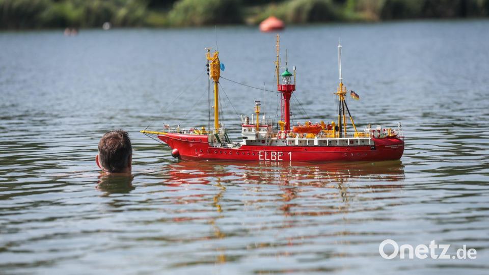 Ein Modellschiff "Elbe 1" fährt im Schwarzachtalsee an einem Schwimmer vorbei. Bild: Thomas Warnack/dpa