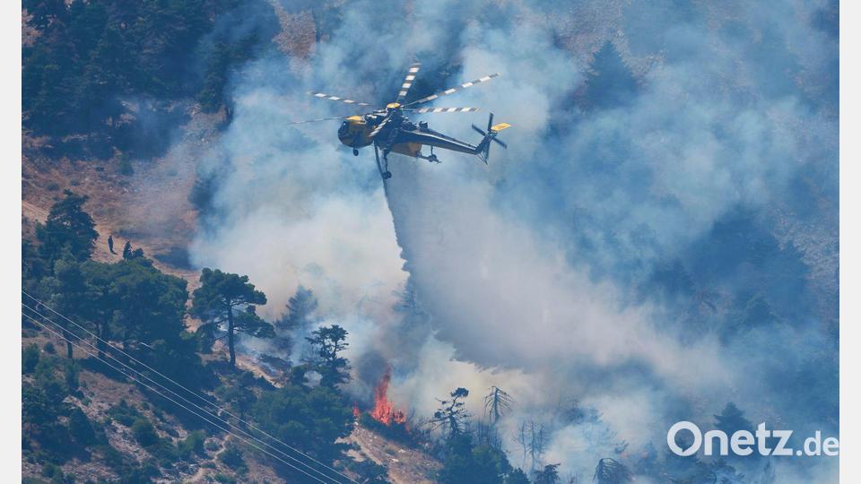 Ein Löschhubschrauber wirft Wasser über einem Waldbrand nordwestlich von Athen ab. Bild: Petros Giannakouris/AP/dpa