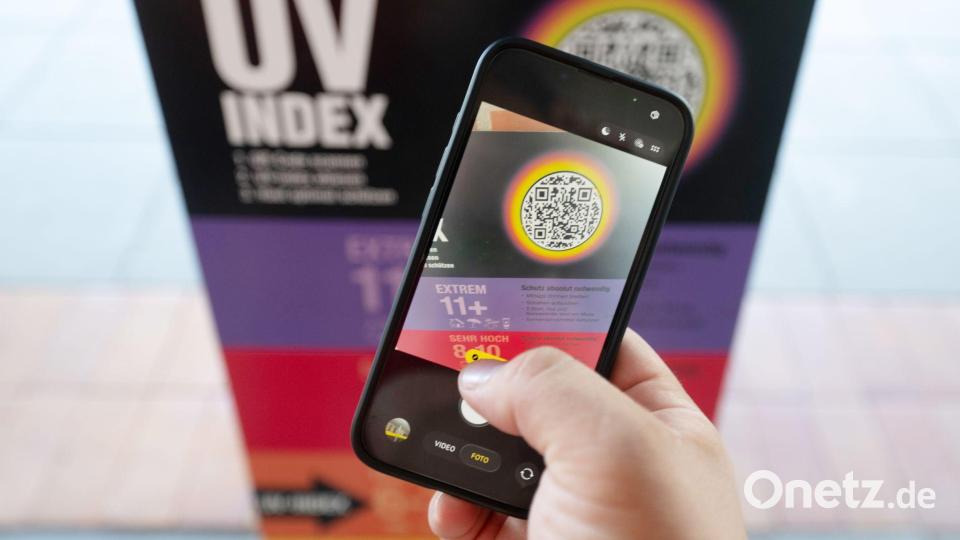 Ein Bademeister scannt am Vormittag eine UV-Index Anzeige mit einem Smartphone. Bild: Marijan Murat/dpa