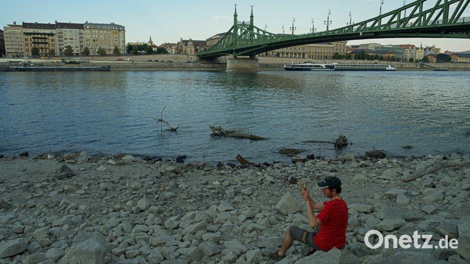Unter der Freiheitsbrücke lässt sich's nun im Trockenen sitzen. Bild: Bela Szandelszky/AP/dpa