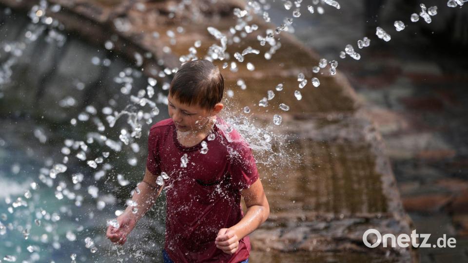 Ein Junge kühlt sich an einem heißen Sommertag in einem Springbrunnen in Moskau ab. Bild: Pavel Bednyakov/AP/dpa