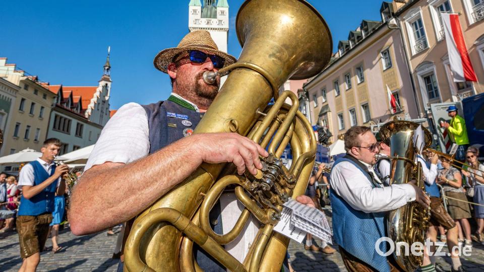 Teilnehmer des traditionellen Auszugs zum Gäubodenvolksfest gehen in Tracht und mit Blasinstrumenten durch die Innenstadt von Straubing. Bild: Armin Weigel/dpa