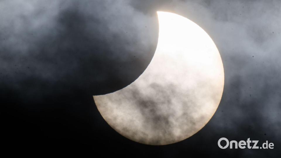 Eine partielle Sonnenfinsternis ist zwischen Wolken am Himmel zu sehen. (Archivbild) Bild: Julian Stratenschulte/dpa