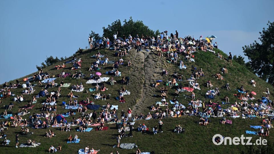 Erste Besucher bevölkern den Olympiaberg im Münchner Olympiapark, um von dort die partielle Sonnenfinsternis zu beobachten. Bild: Felix Hörhager/dpa