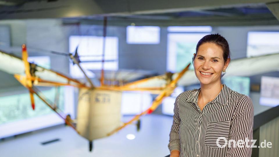 Museumsleiterin Laura Gebauer vor dem Nachbau des vielleicht ersten Motorflugzeugs der Welt. Bild: Daniel Karmann/dpa