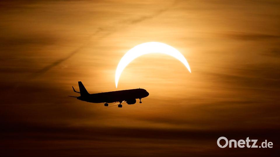 Ein Airbus A321 aus London fliegt während der partiellen Sonnenfinsternis im Landeanflug auf den Flughafen Berlin Brandenburg (BER) vor der teilweise vom Mond verdeckten Sonne. Bild: Michael Ukas/dpa