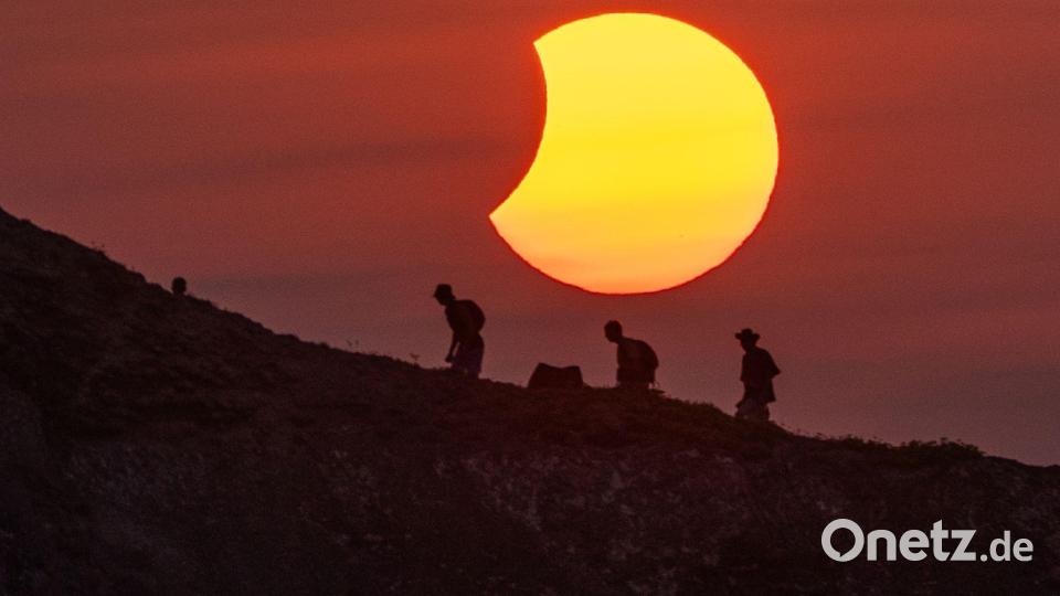 Besucher gehen nach der totalen Sonnenfinsternis auf einer Klippe oberhalb des Strandes von Ajo in Kantabrien in Spanien, während der Mondschatten wieder von der Sonne wegwandert. Bild: Michael Kappeler/dpa