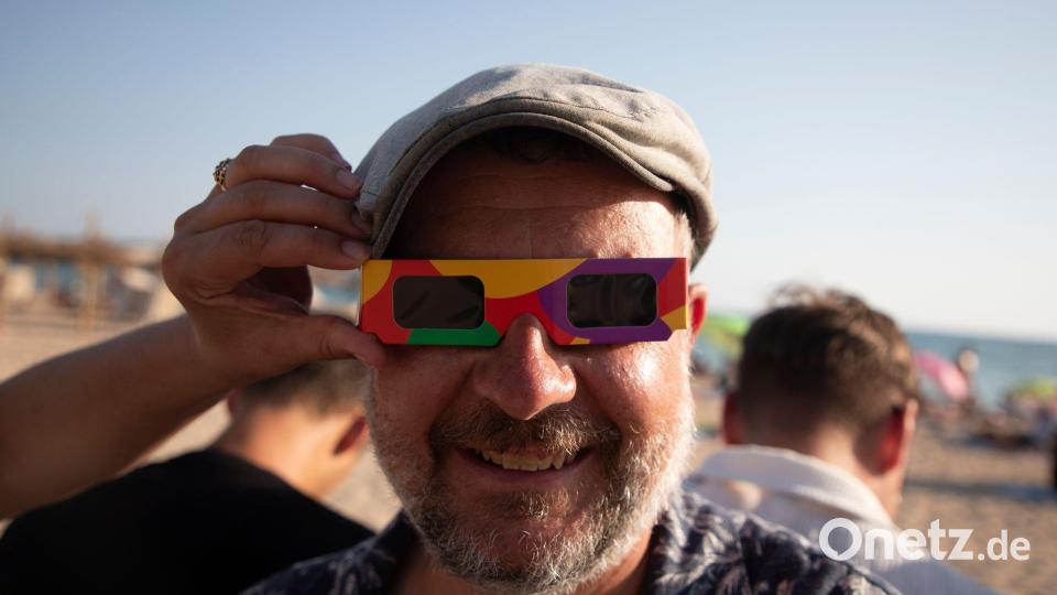 Peter from aus Ungarn bereitet sich mit einer Sonnenfinsternisbrille am Strand von Palma auf die totale Sonnenfinsternis vor. Bild: Clara Margais/dpa