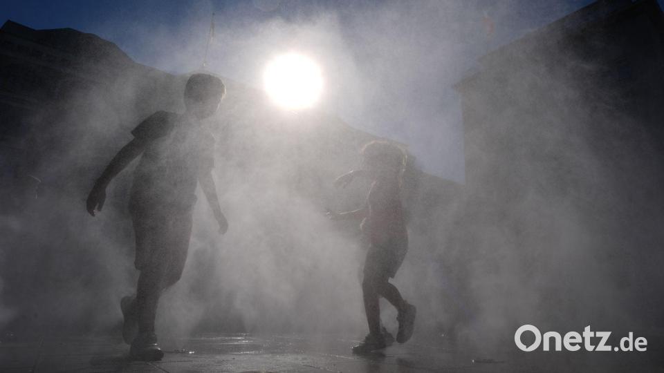Kinder kühlen sich in einem Wassersprühnebel am Jungfernstieg in der Innenstadt ab. Bild: Marcus Brandt/dpa