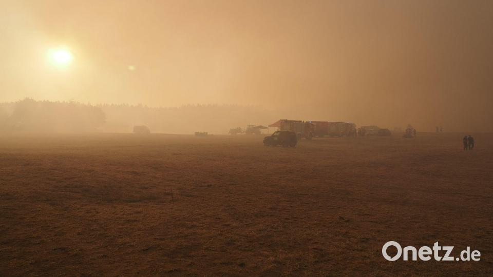 Feuerwehrfahrzeuge werden an einem Sammelpunkt vom Qualm eines Waldbrandes in der Nähe des Ortsteils Großhau in der Gemeinde Hürtgenwald eingehüllt. Bild: Georg Hilgemann/dpa