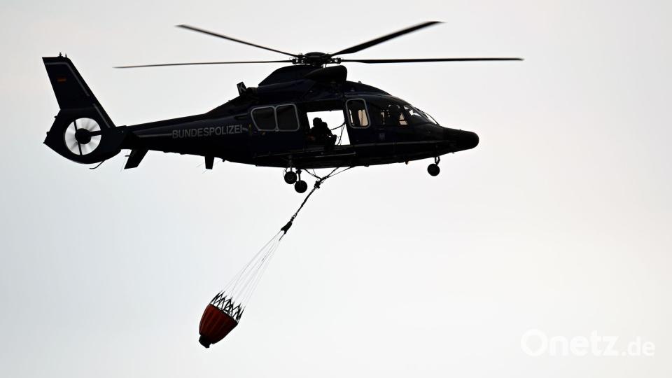 Ein Hubschrauber der Polizei fliegt über Kleinhau. Bild: Federico Gambarini/dpa