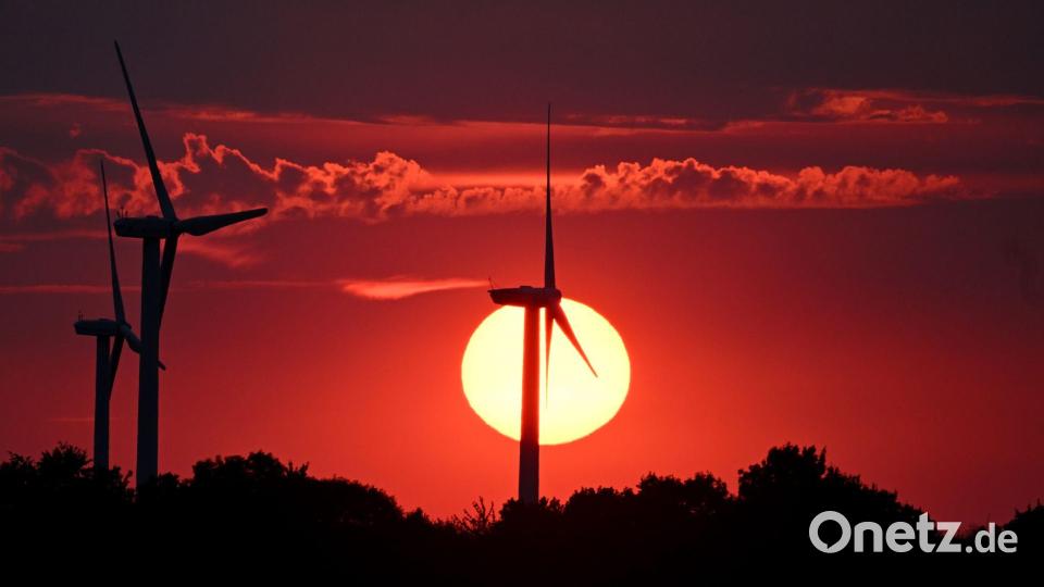 Hinter Windrädern färbt die sinkende Sonne den Himmel über Nordrhein-Westfalen rot. Bild: Federico Gambarini/dpa