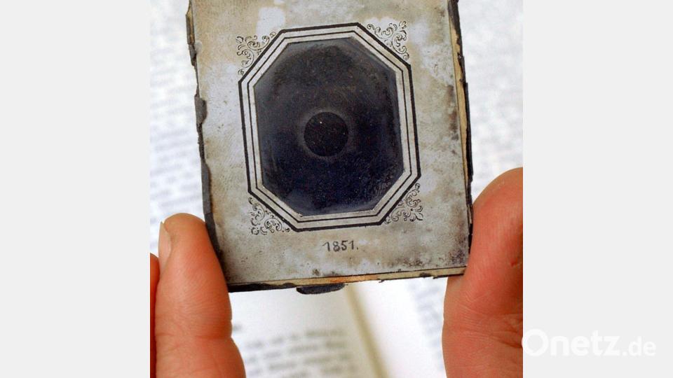 Ein Mann zeigt die älteste, der Fachwelt bekannte fotografische Aufnahme einer Sonnenkorona bei einer totalen Sonnenfinsternis am 28. Juli 1851 an der Sternwarte der Friedrich-Schiller-Universität Jena. Die nur wenige Zentimeter große Daguerreotypie wurde mit einem Heliometer in Königsberg (heute Kaliningrad) von einem Daguerreotypist namens Berkawski aufgenommen. Seit 1901 gehört eine der von Berkowski angefertigten Kopien der Original-Daguerreotypie zur Astronomischen Sammlung des Astrophysikalischen Instituts der Friedrich-Schiller-Universität Jena. 2026 feiert die Fotografie in vielen Ländern ihr 200-jähriges Jubiläum. Bild: Jan-Peter Kasper/dpa