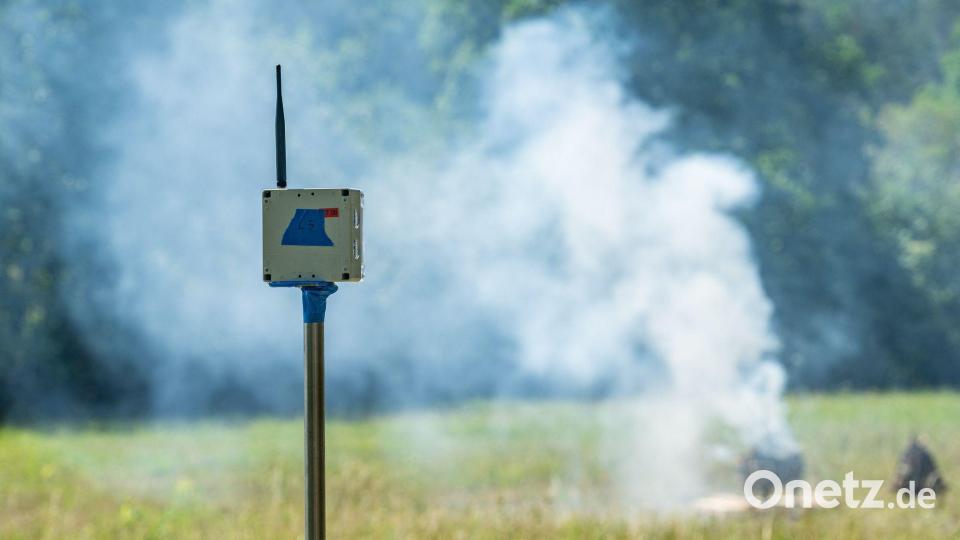 Ein Sensor zur Waldbrandfrüherkennung steht vor einem künstlich erzeugten Brand. Bild: Armin Weigel/dpa