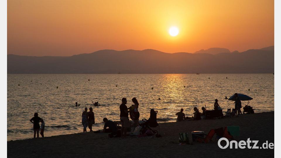 Am Strand von Playa de Palma auf Mallorca baden Menschen bei Sonnenuntergang im Meer. (Archivbild) Bild: Clara Margais/dpa