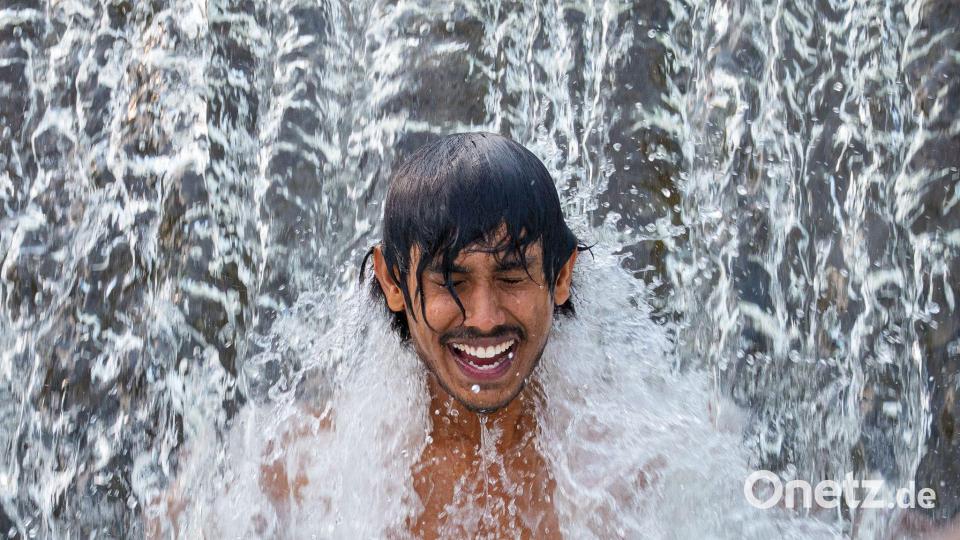 Ein Gastarbeiter aus Sri Lanka kühlt sich an einem glühend heißen Tag in einer Wasserkaskade eines Flusses außerhalb der Stadt Bragadiru in Rumänien ab. Bild: Andreea Alexandru/AP/dpa