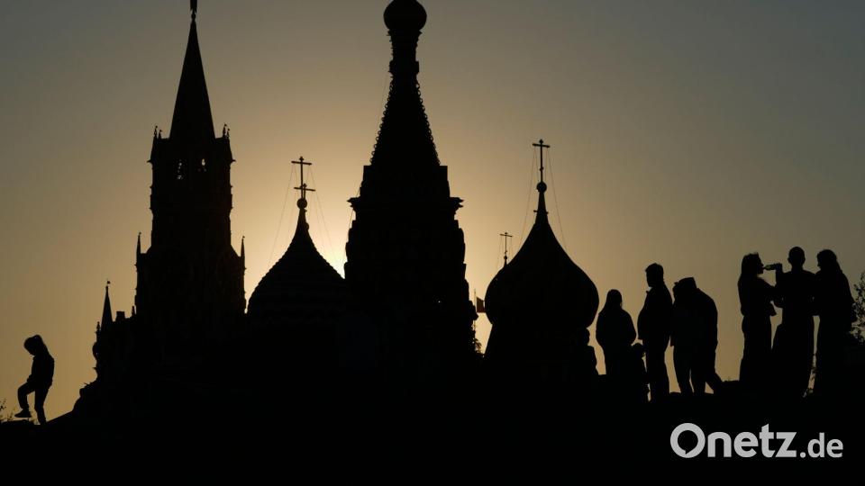 Menschen spazieren bei Sonnenuntergang im Zaryadye-Park in Moskau vor dem Hintergrund des Spasskaja-Turms des Kremls und der Basilius-Kathedrale. Bild: Pavel Bednyakov/AP/dpa