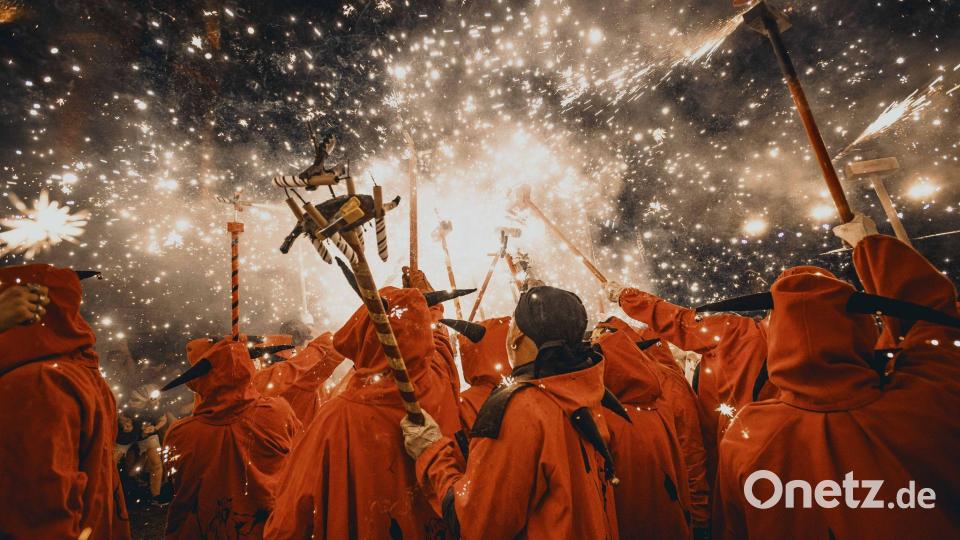 Feuerläufer entzünden beim traditionellen „Correfoc“ bei der Festa Major de Gracia ihre Feuerwerksstäbe unter einem Funkenregen . Bild: Matthias Oesterle/ZUMA Press Wire/dpa