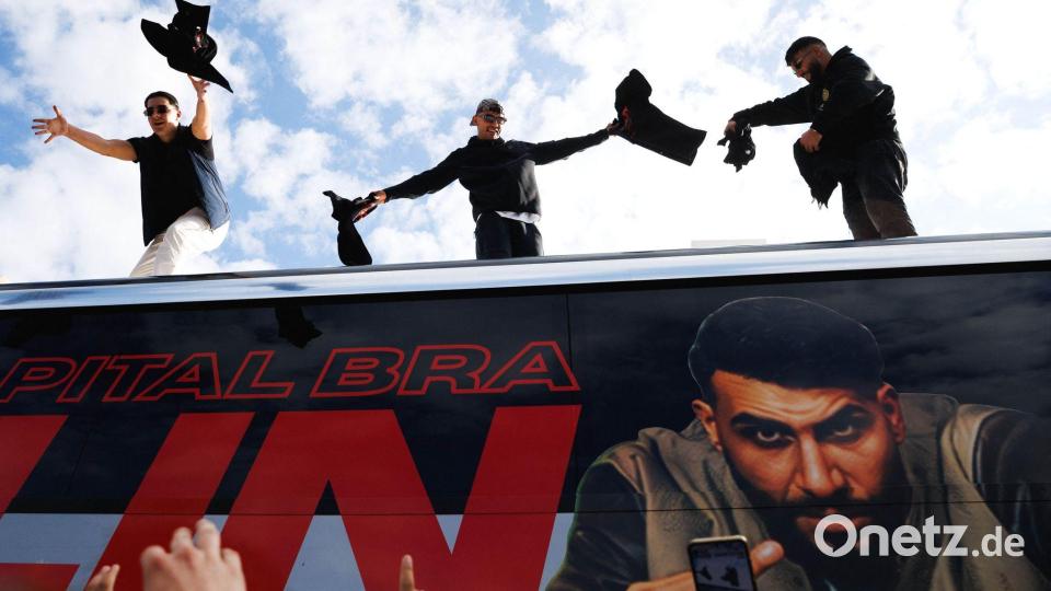 Die Rapper Lacazette, Capital Bra und Samra werfen bei einer Fanaktion in Kreuzberg T-Shirts von einem Tourbus. Bild: Carsten Koall/dpa