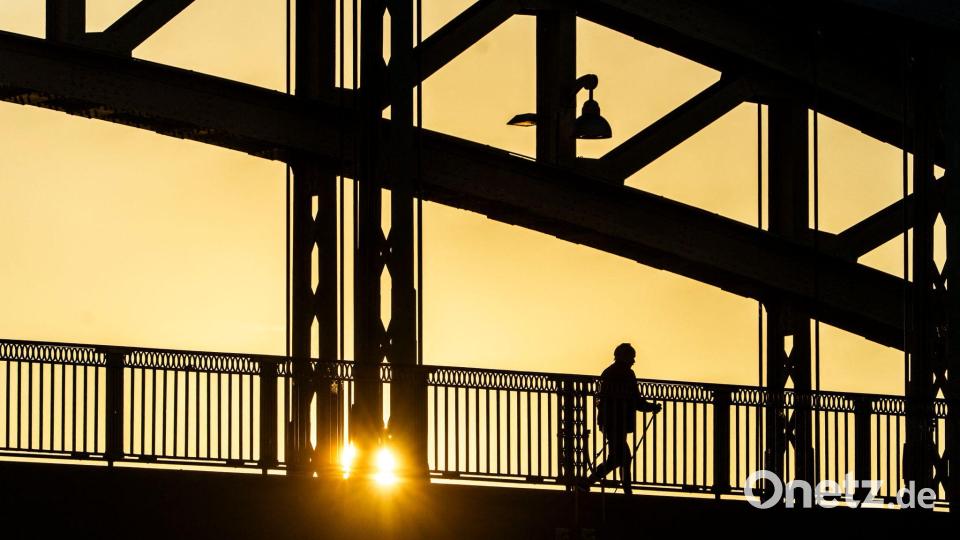 Frühsport im Sonnenaufgang - Nordic Walker auf der Osthafenbrücke in Frankfurt. Bild: Andreas Arnold/dpa