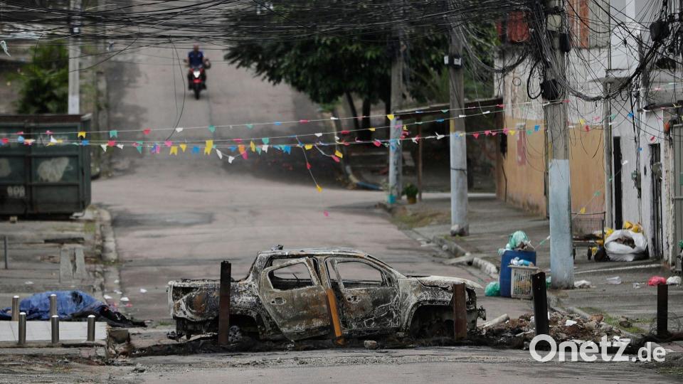 Ein ausgebranntes Auto versperrt eine Straße in der Favela „Complexo de Israel“, nahe weiterer Favelas, in denen die Polizei derzeit Razzien gegen Drogenbanden durchführt. Bild: Bruna Prado/AP/dpa