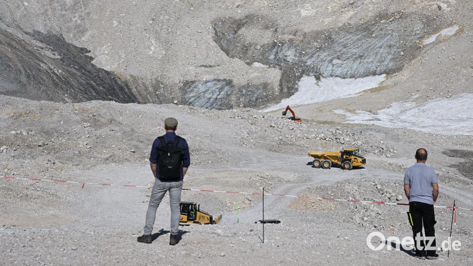 Wanderer beobachten Baumaschinen neben den Überresten des Nördlichen Schneeferner-Gletschers auf der Zugspitze. (Archivbild) Bild: Angelika Warmuth/dpa