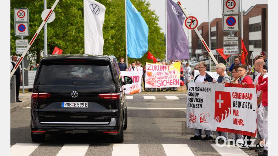 Ein VW-Bus mit VW-Vorstandschef Oliver Blume passiert die Demonstration von Beschäftigten am Werkstor des Standortes Zwickau. Bild: Hendrik Schmidt/dpa