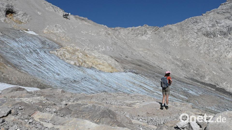 Eine Wandererin vor dem Nördlichen Schneeferner Gletscher unterhalb der Zugspitze. Bild: Angelika Warmuth/dpa