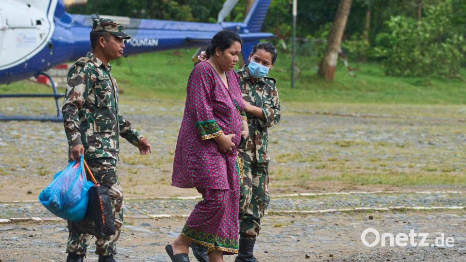 Soldaten der nepalesischen Armee helfen einer schwangeren Frau, einen Hubschrauber zu erreichen. Bild: Niranjan Shrestha/AP/dpa