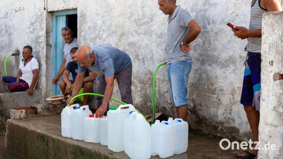 Menschen in Tunesien befüllen Wasserbehälter mit Trinkwasser. Bild: Anis Mili/AP/dpa
