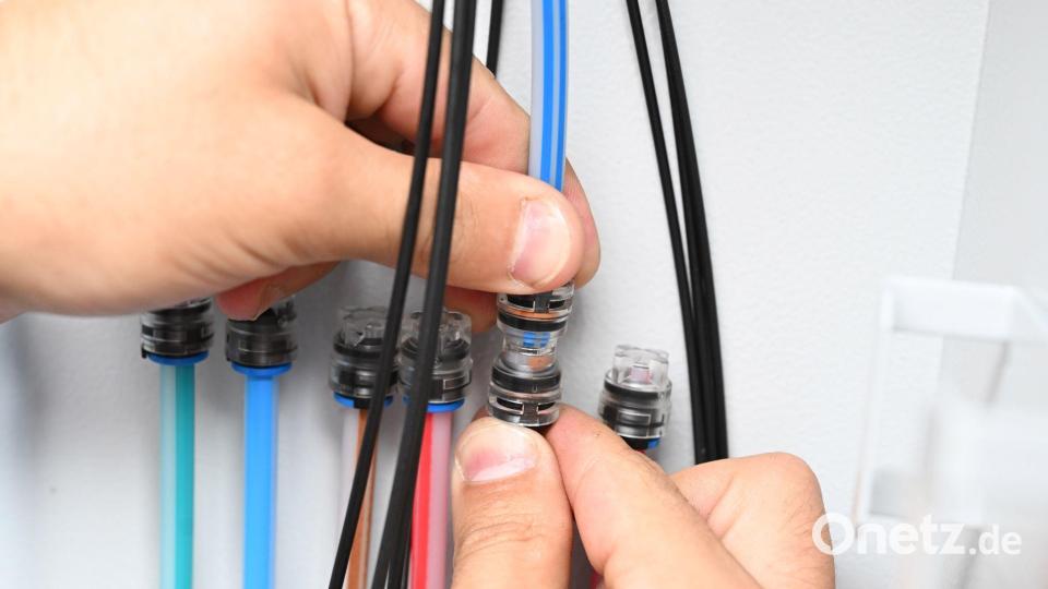 Ein Techniker verbindet Glasfaser-Kabel, um besonders schnelles Internet zu ermöglichen. Bild: Bernd Weißbrod/dpa