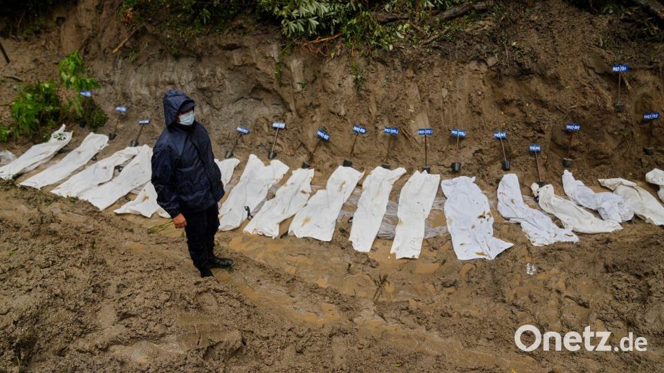 Ein nepalesischer Polizist steht neben einer Reihe von Leichen von Opfern der Sturzflut, die zur Beisetzung in einem Massengrab aufgebahrt wurden. Bild: Dar Yasin/AP/dpa