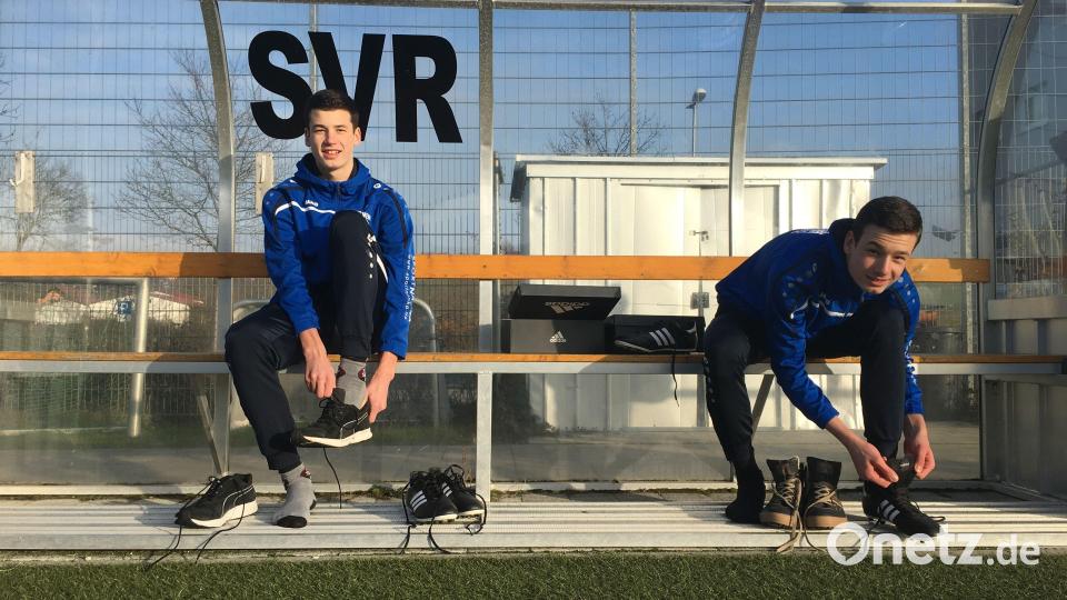 Tim und Leon Schreiner sitzen im Pandurenpark beim SV Raigering auf der Bank und schnüren ihre Schuhe in Größe 50. Bild: roa