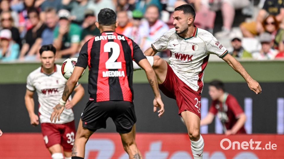 Leverkusens Facundo Medina (links) und Arijon Ibrahimovic vom FC Augsburg kämpfen um den Ball. Bild: Harry Langer/dpa